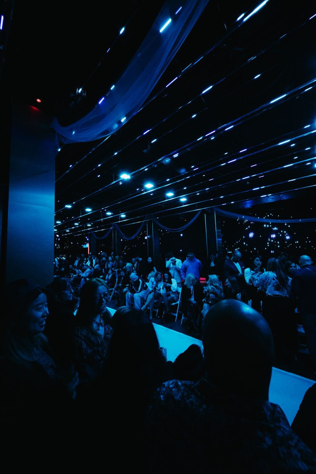 Guests gathered under dramatic blue overhead lighting