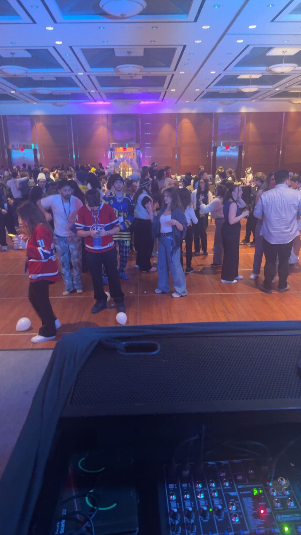 A packed dance floor lit in blue and purple