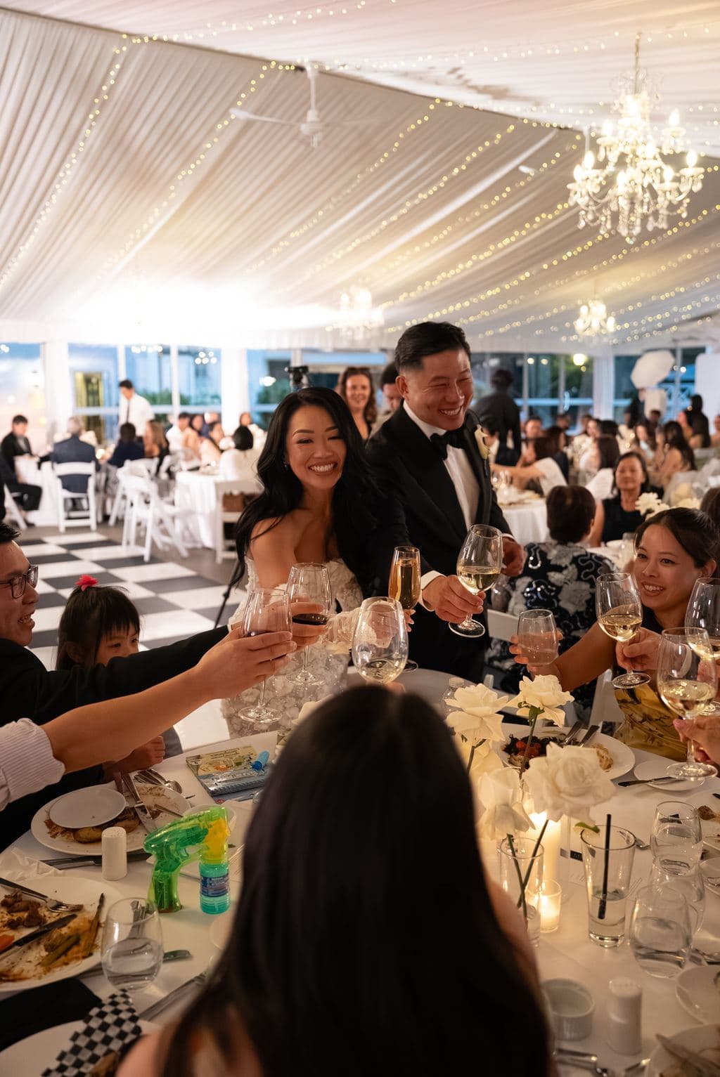 Wedding guests raising a toast at a candlelit reception table