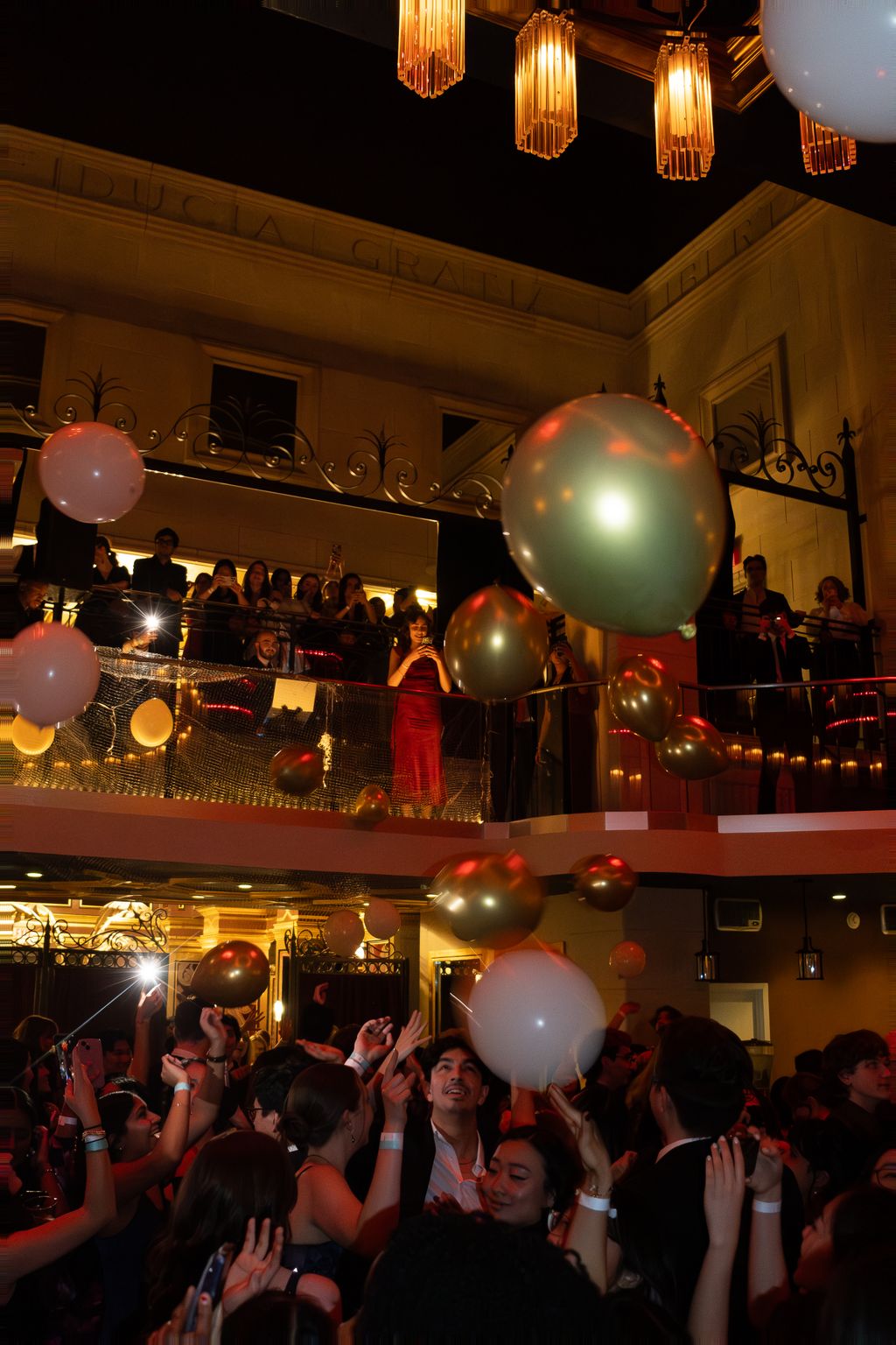 Balloon drop over a crowd celebrating in a grand hall