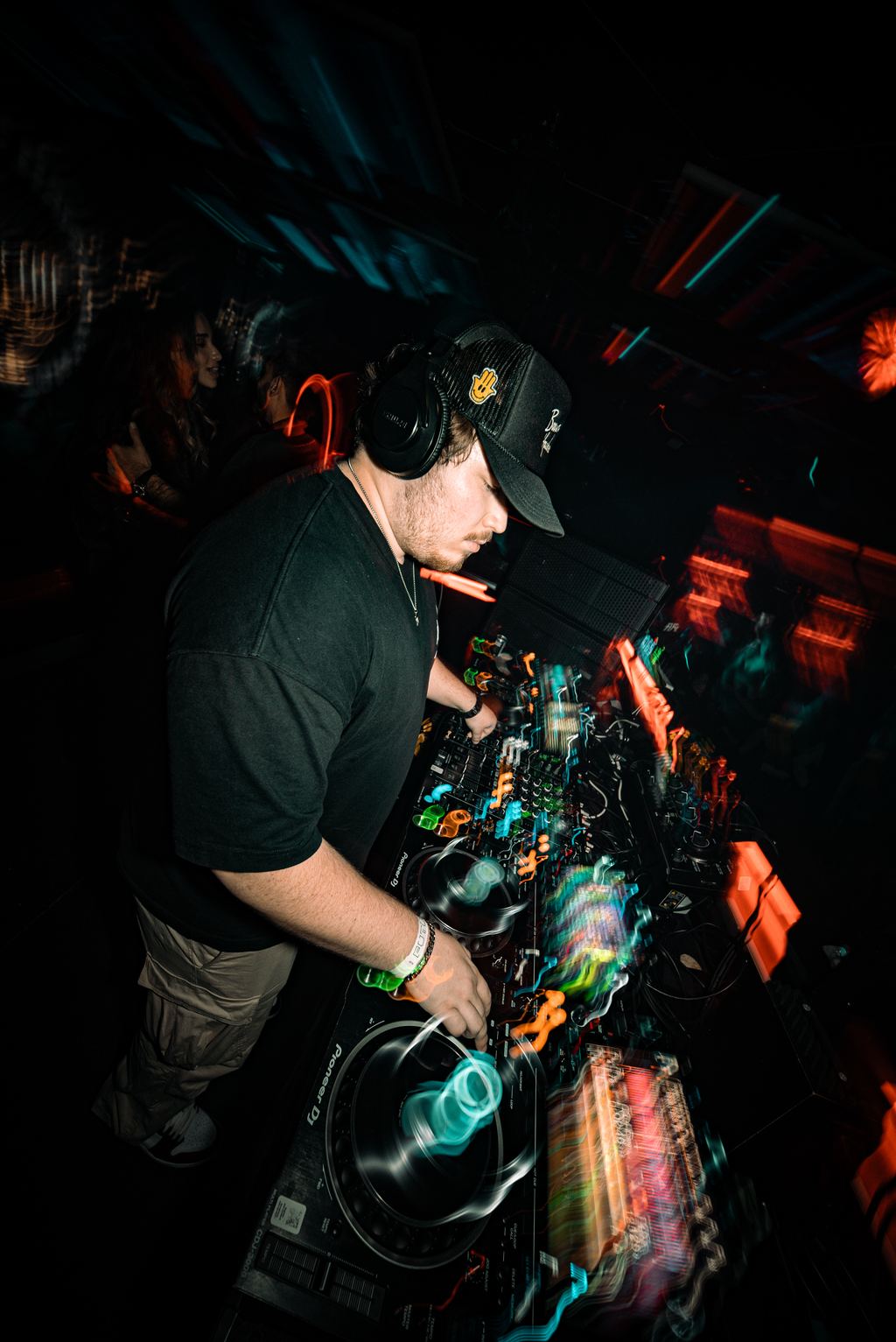 DJ mixing at the booth under colorful motion-blurred lighting