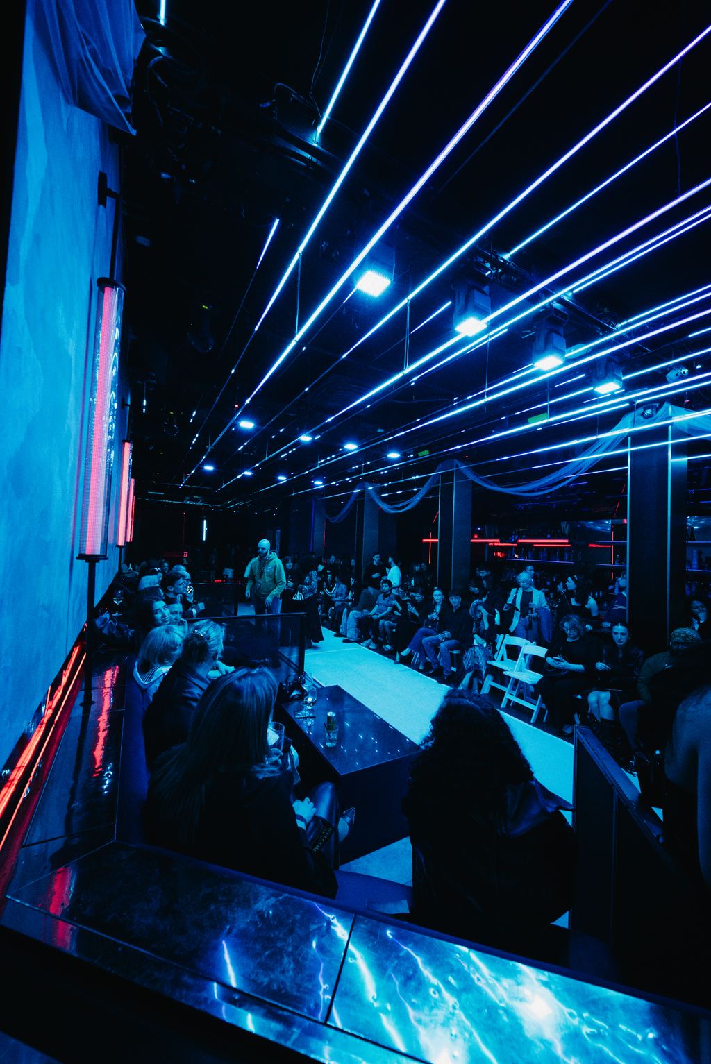 Dramatic overhead lighting beams across a produced event space