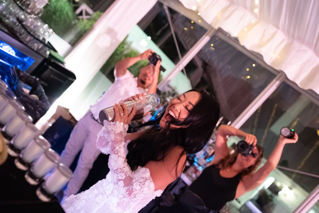A singer performing on mic under string lights as guests cheer alongside