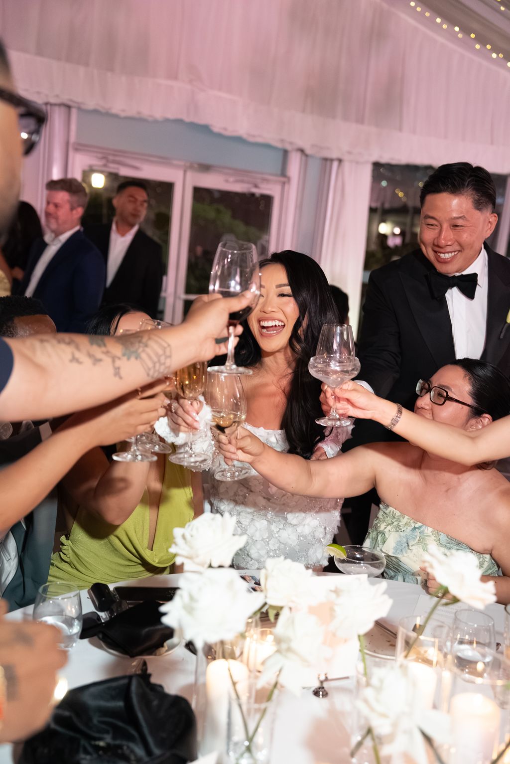 Bride laughing during a champagne toast with guests at the reception table
